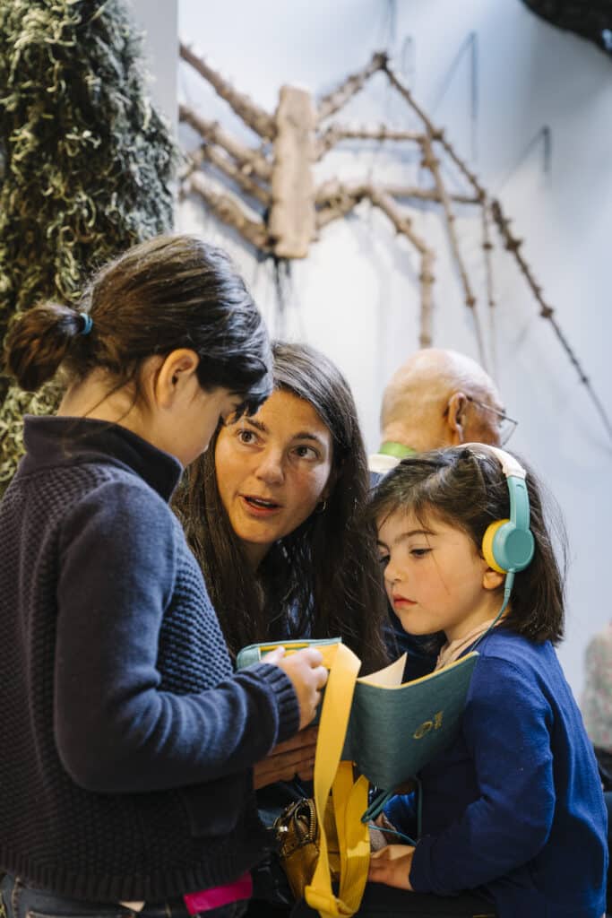 Famille écoutant l'histoire Lunii sur l'exposition Le Chant des Forêts