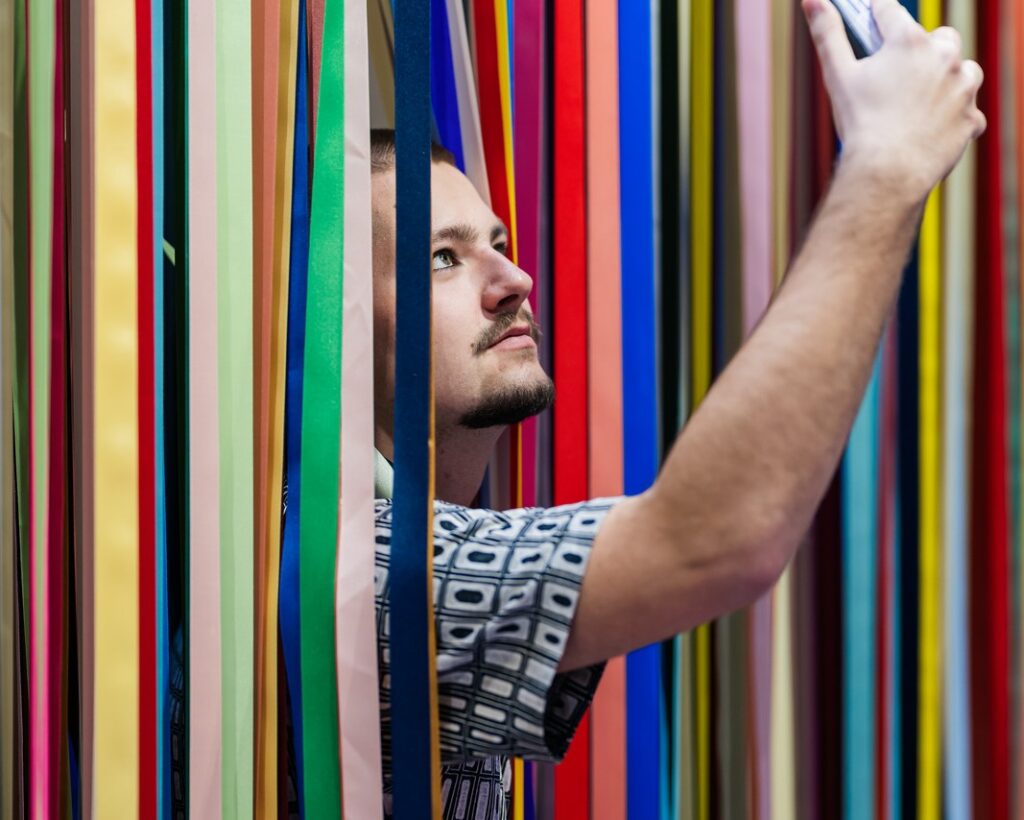 Jeune homme sortant de l'oeuvre " The wonderfull world of abstraction (le merveilleux monde de l'abstraction)"  de l'artiste Jacob Dahlgren dans le cadre de l'exposition Faisons corps du MAIF Social Club