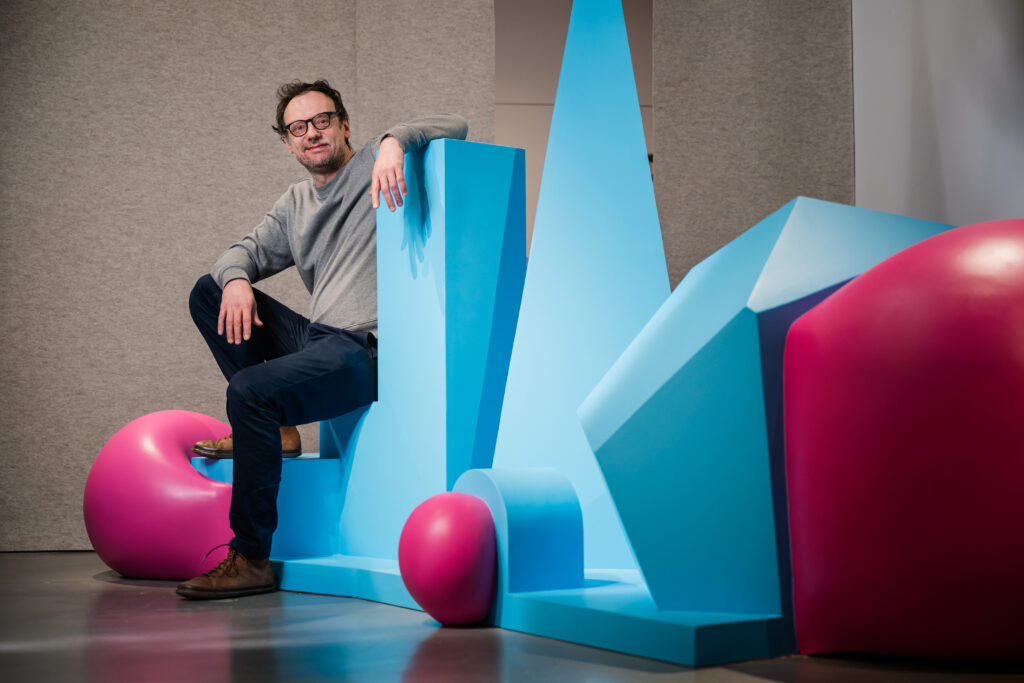 Portrait de Nicolas Guiet, artiste devant son oeuvre au sein de l'exposition "Faisons Corps" au MAIF Social Club, à Paris.