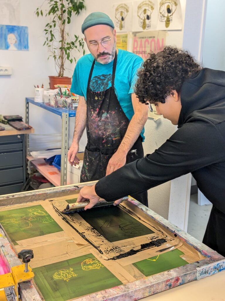 L'artiste avec un élève qui font un atelier serigraphie